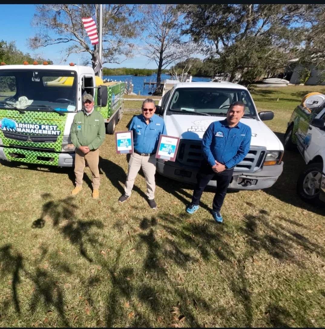 The Rhino Pest Management team with their service trucks on Florida's Treasure Coast, holding their Best of 2023 and 2024 awards
