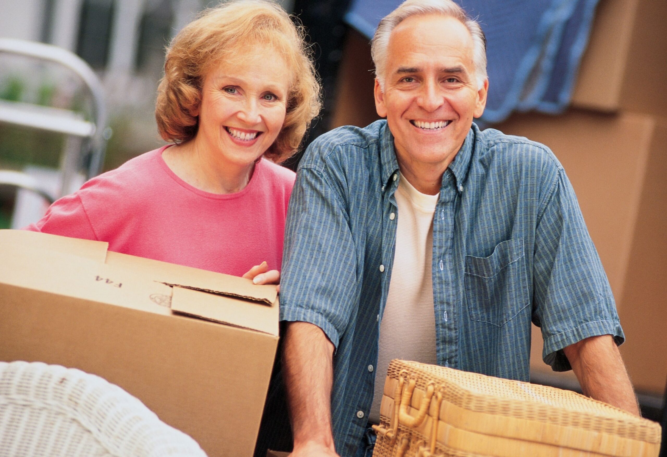 Smiling elderly couple holding moving boxes, symbolizing a stress-free move with Captain Duster’s professional move in and move out cleaning services.