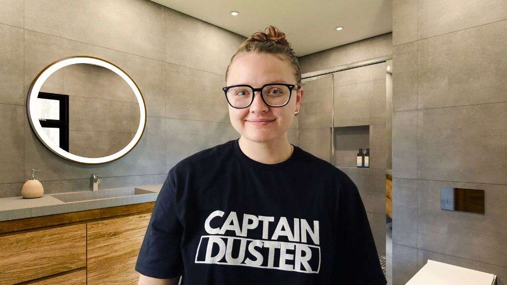 Professional cleaner standing in a spotless bathroom, ready to start a deep clean.